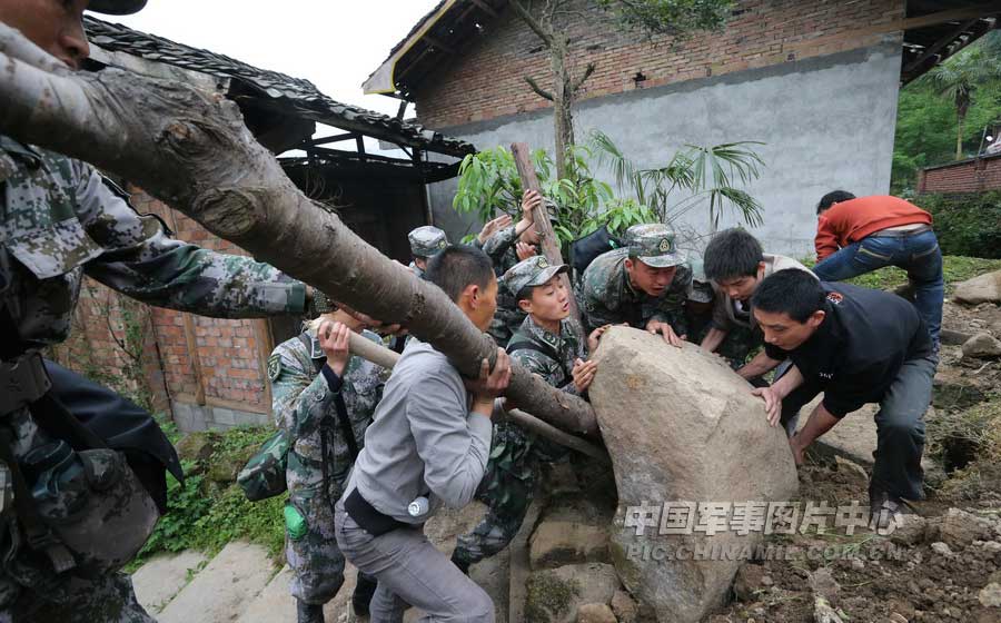 4月21日上午，記者在蘆山地震中心災區太平鎮，攝下了13軍某炮兵團官兵在幫助村民清理路障的情景。