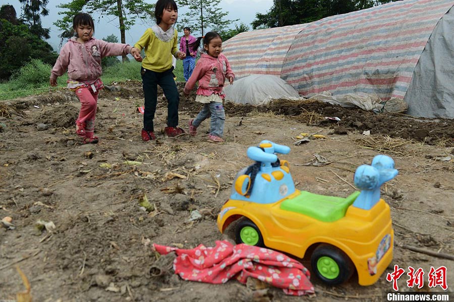 4月21日，四川雅安蘆山縣龍門鄉(xiāng)三個(gè)小孩在一輛玩具車前走過。中新社發(fā) 張?jiān)?攝